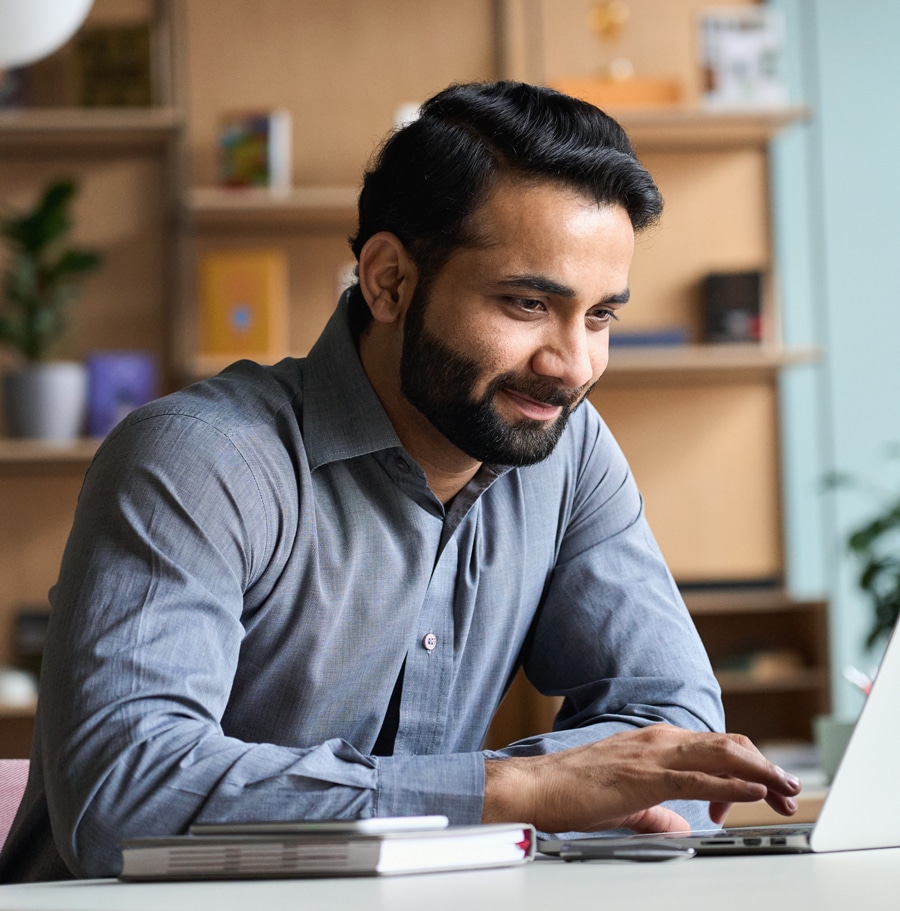 a man sitting at a desk and using a laptop computer
